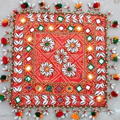 an orange and white square with pom poms on the sides, surrounded by small beads