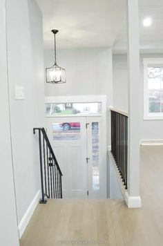 an empty house with white walls and black railings on the front door, along with a light wood floor