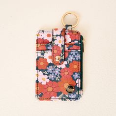 a flowered wallet with a gold keychain hanging from it's side