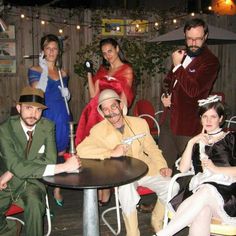 a group of people sitting around a table in front of a man with an umbrella