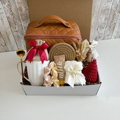 a gift box filled with assorted items on top of a white table next to a wooden wall