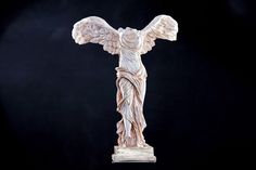 a statue of an angel with outstretched wings on a white pedestal against a black background