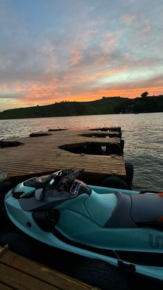 there is a jet ski parked on the dock at sunset or dawn, with other boats in the water