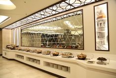 a buffet area with many different foods on the counter and in front of a large mirror