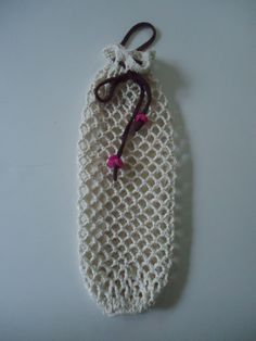 a white crocheted bag with a pink flower on the side and a brown string