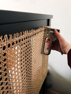 a person holding a pair of scissors near a piece of woven material on a wall