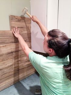 a woman using a brush to paint the wood paneling on a wall with planks