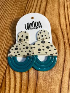 two pairs of earrings with polka dots on them sitting on top of a wooden table