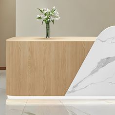 a vase with flowers sitting on top of a marble counter next to a wooden cabinet