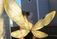 a woman wearing a butterfly costume standing in front of a house with her back to the camera