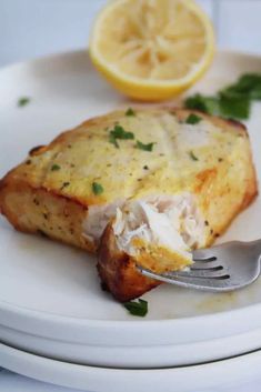 a white plate topped with food and a fork next to a lemon wedge on top of it