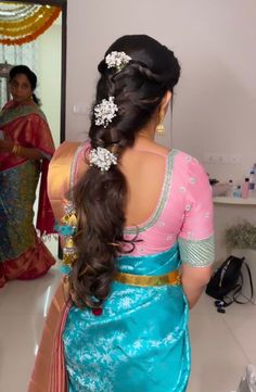 a woman in a blue and pink sari is looking at herself in the mirror