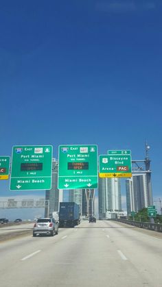 three green signs on the side of a highway