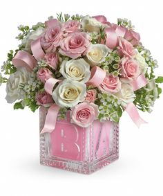 pink and white flowers are in a square vase with ribbon around the edges, along with baby's breath