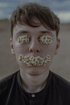 a young man with fake daisies on his face and nose is seen in this image