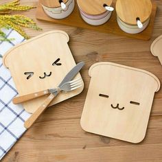 three pieces of wooden bread with faces on them, one has a knife and fork in it