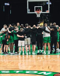 a group of men standing on top of a basketball court with their arms around each other