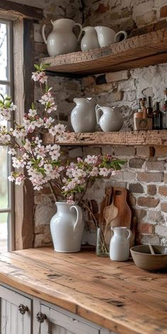 a kitchen counter topped with white vases filled with flowers next to a brick wall