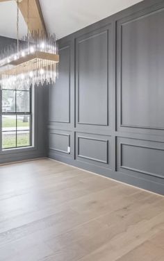 an empty room with gray walls and chandelier