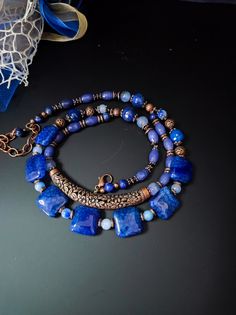 This is an ethnic style necklace made with large square dragon venis agate stones dyed blue. The necklace is double-stranded with a copper-plated brass decorative element in the center. To finish the necklace I also used agate, jade and lapiz stones. For those who love elegant retro style. All jewels are delivered in a decorated box, ready to be given as a gift to your loved one. How to take care of your jewellery: put on your beauty products (cosmetics, perfumes, ...) before wearing your precious jewel. Clean your jewelry with a soft cloth after wearing. Don't use water. Make sure you store your jewelry separately to avoid scratching it. Store away from heat sources, in a dry place in the special box. SHIPPING CONDITIONS I ship to the address you provided to us on Etsy, so be sure to chec Blue Square Necklace For Gifts, Blue Square Necklace For Gift, Blue Square Necklace Perfect For Gifts, Bohemian Blue Rectangular Necklace, Handmade Blue Rectangular Necklace, Artisan Blue Rectangular Necklace, Bohemian Square Necklace As Gift, Bohemian Square Necklace Gift, Bohemian Square Necklace For Gift