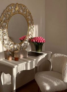 a white desk topped with a mirror and pink flowers