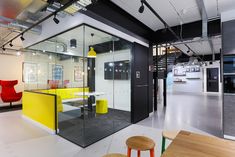 an office with glass walls and yellow chairs