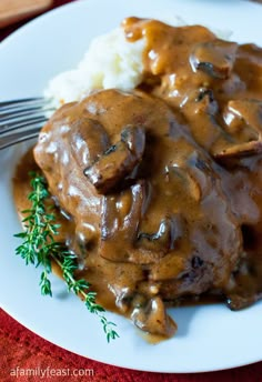 a white plate topped with meat covered in gravy