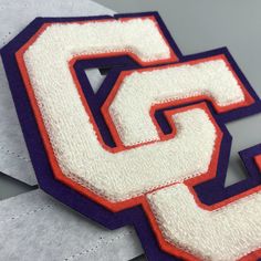 the letter s is made out of white and purple material with an orange stripe on it