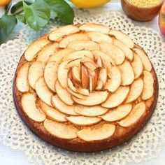 an apple cake on a doily with apples around it