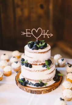 a wedding cake with berries on top and the words, rustic wedding arrow cake topper