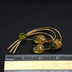 "*Description: This is a beautiful Sarah Coventry brooch entitled \"Touch of Elegance\" which has three green Austrian crystal faceted oval stones with gold tone filigree flower tops from the 1970s. Each flower top has a green rhinestone chaton with a larger green rhinestone chaton placed on the stems. This brooch is a book piece and is found on page 100 of Sarah Coventry Jewelry by Kay Oshel. The brooch is also featured in The Art of Juliana Jewelry by Katerina Musetti. This would be a great ad Antique Green Brooch For Evening, Mid-century Green Brooch For Formal Occasions, Mid-century Green Brooches For Formal Occasions, Vintage Green Brooch Jewelry, Antique Green Brooch For Anniversary, Vintage Green Brooch For Evening, Victorian Green Collectible Brooches, Antique Green Brooches For Anniversary, Vintage Green Evening Brooch