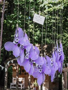 purple flowers hanging from strings in front of trees