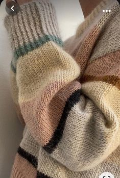 an image of someone's hand with their arm wrapped in a knitted sweater