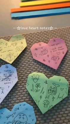 four hearts with writing on them sitting next to colored pencils