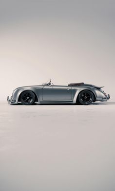 an old silver sports car parked on top of a white floor