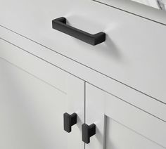 a white dresser with black handles and knobs