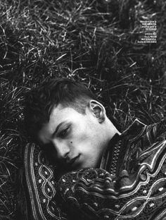 a man laying in the grass with his head on his chest and eyes closed, wearing a sweater