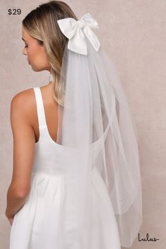 a woman wearing a white veil with a bow on the back of her wedding dress