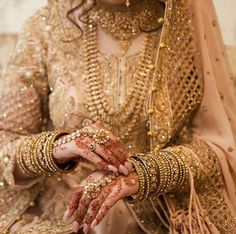 a woman wearing gold jewelry and holding her hands