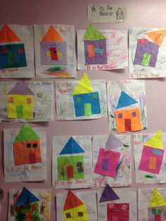 a group of children's handmade houses are displayed on a bulletin board in the classroom