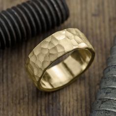 a gold ring sitting on top of a wooden table next to a black pen and knife