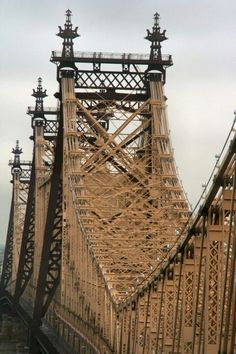 an old yellow bridge that is going over the water with lots of wires on it