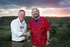 two men standing next to each other in front of a sunset