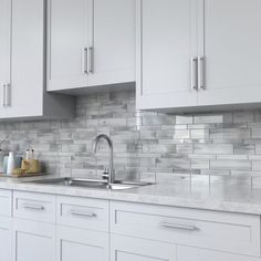 a kitchen with white cabinets and marble counter tops, along with stainless steel sink faucets