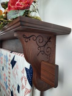 a wooden shelf holding a quilt and flowers