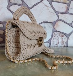 a beige purse sitting on top of a floor next to a wall with a chain hanging from it