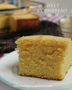 a piece of cornbread on a plate with the rest of the cake in the background