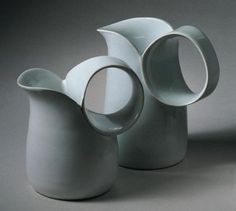 three white vases sitting next to each other on a gray surface with no one around them