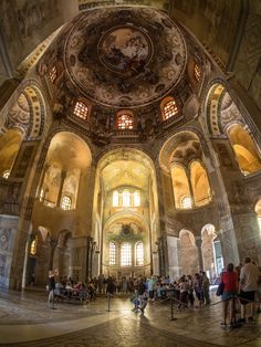 the inside of a building with people sitting and standing around in front of it's windows