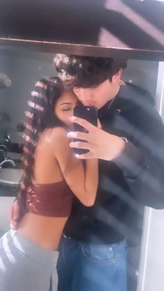 a man and woman taking a selfie in front of a mirror with their arms around each other